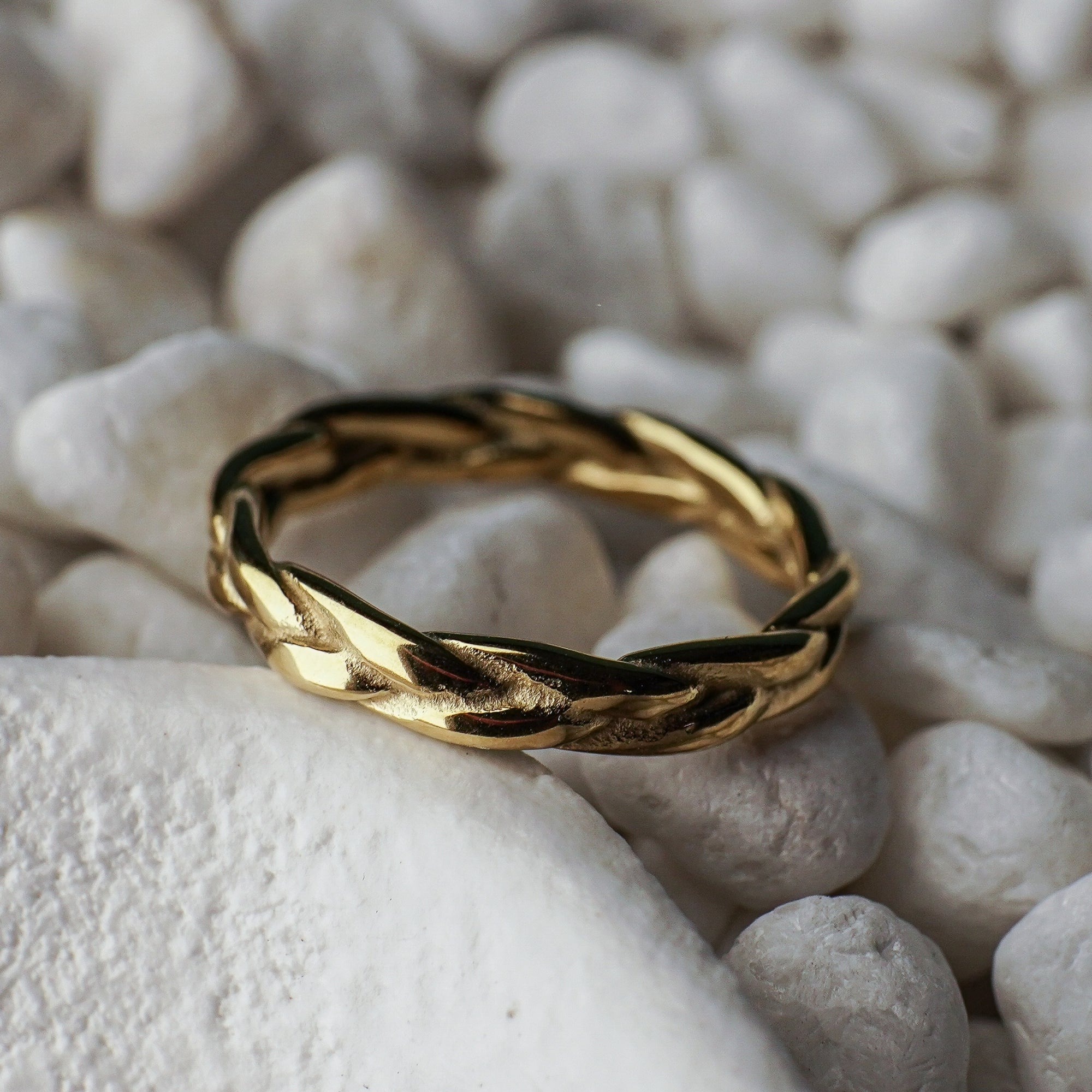 Gold braided ring on a textured white surface