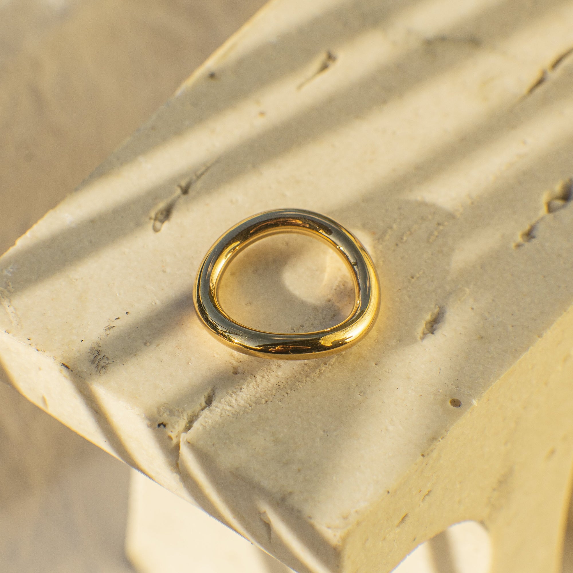 Gold ring on a textured beige surface