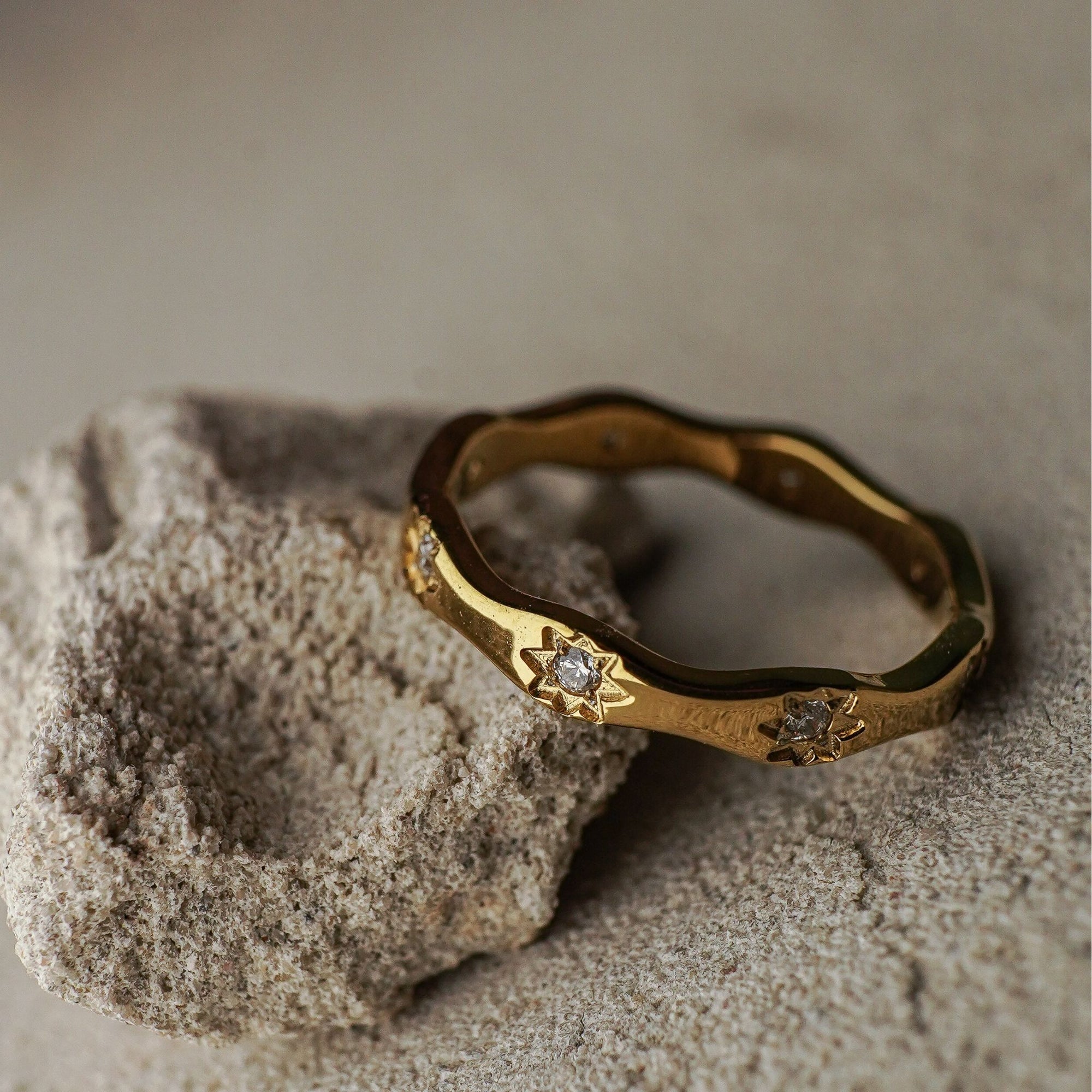 Gold ring with gemstones on a textured stone surface