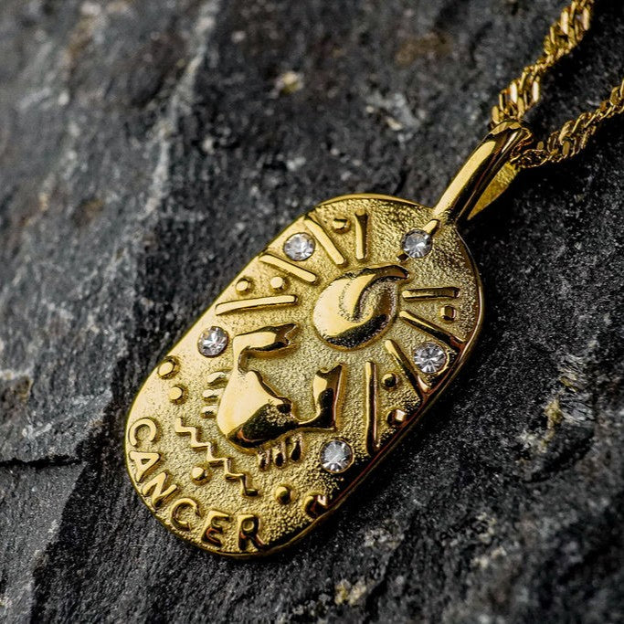 Gold pendant with Cancer Zodiac Sign on a dark stone background
