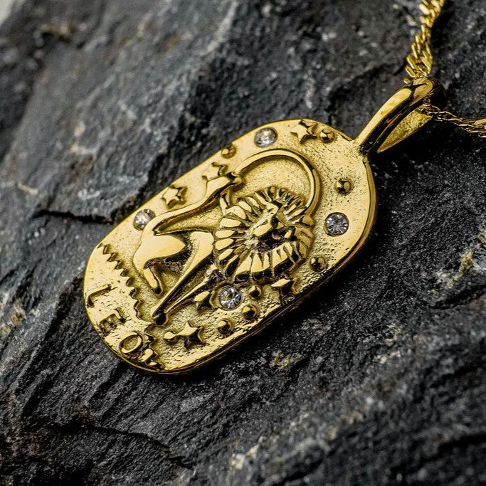 Gold pendant with Leo Zodiac Sign design on a dark stone surface