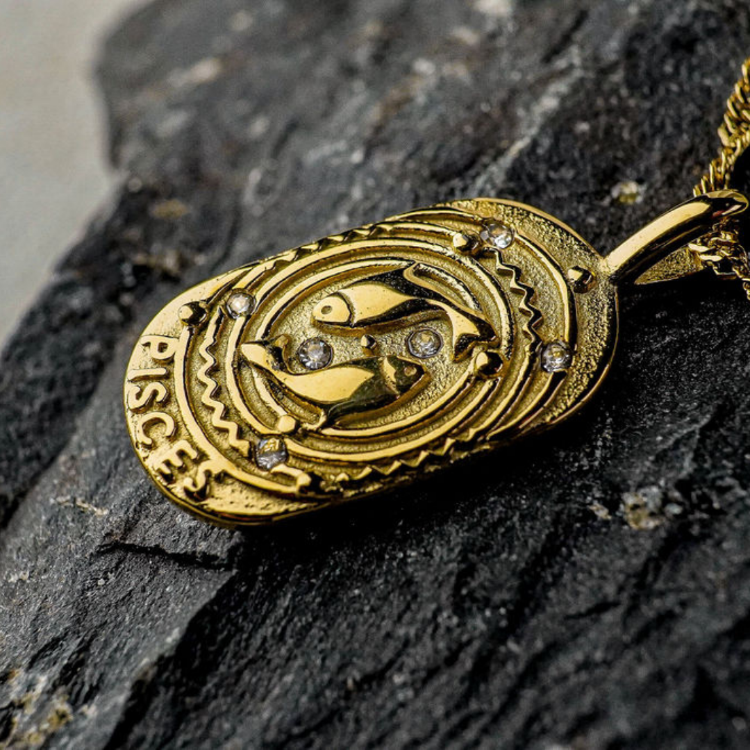 Gold Pisces Zodiac Sign pendant on a dark stone surface