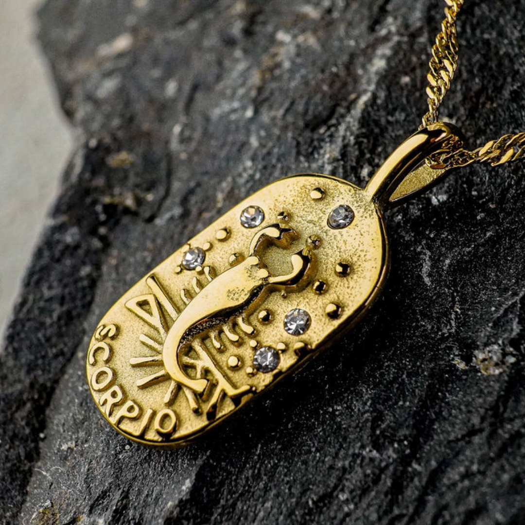 Gold Scorpio Zodiac Sign pendant on a dark stone surface