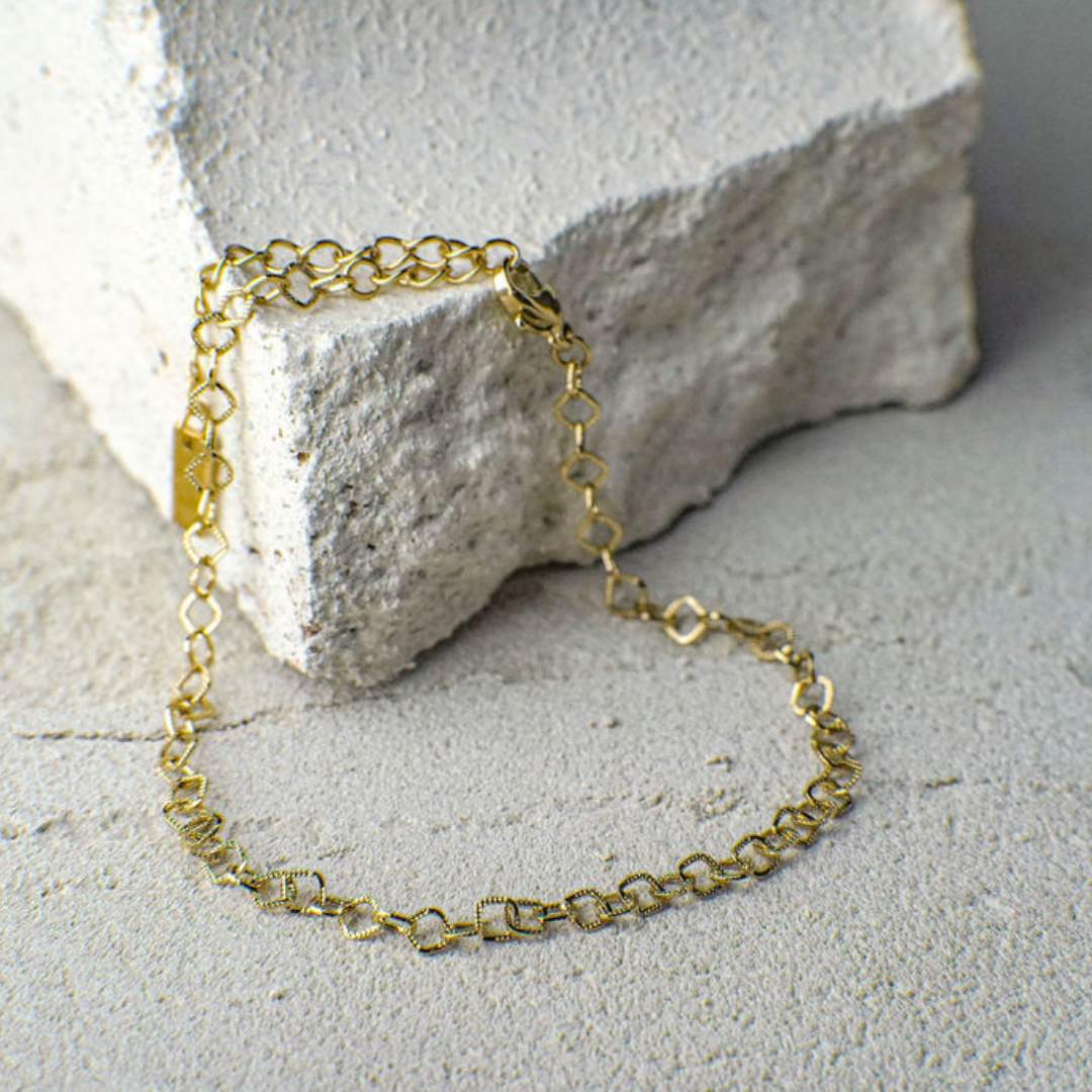 Gold chain bracelet on a textured stone surface