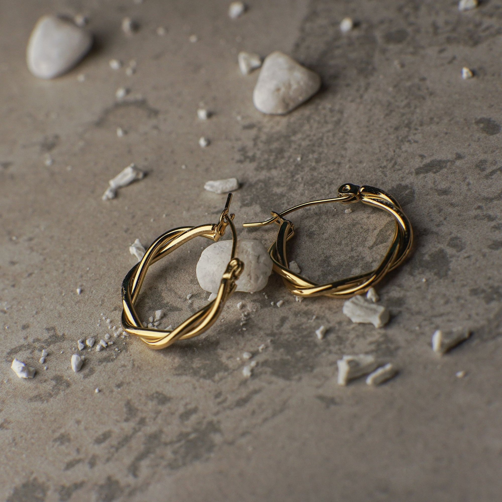 Gold hoop earrings on a textured surface with small stones