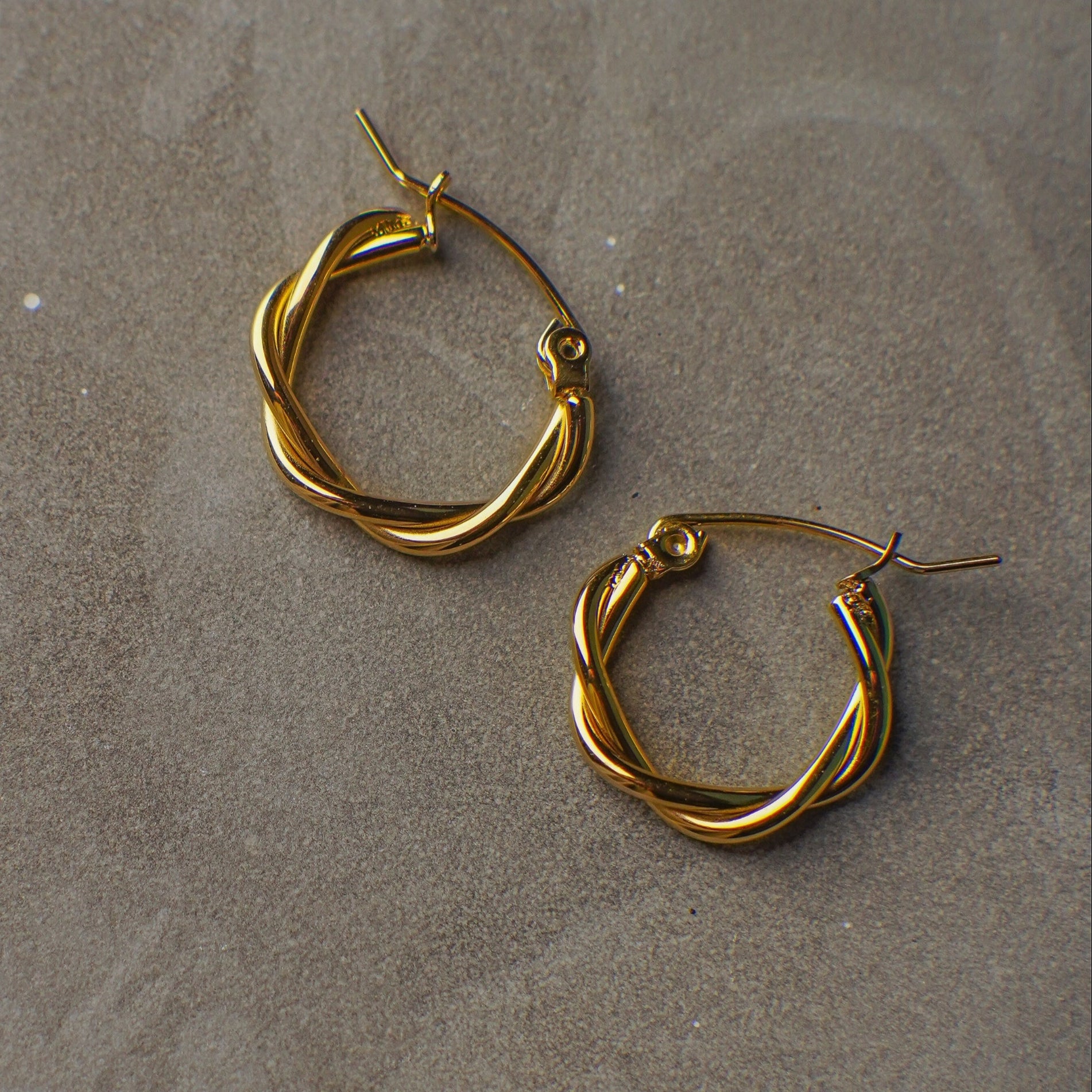 Gold hoop earrings on a gray surface
