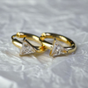 Gold hoop earrings with triangle-shaped gemstones on a textured gray background