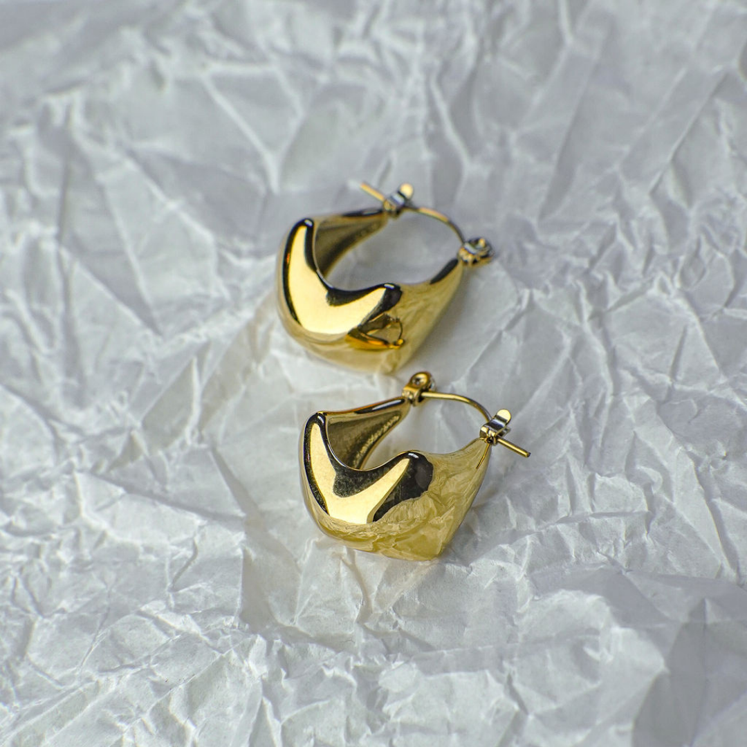 Gold hoop earrings on a textured white background