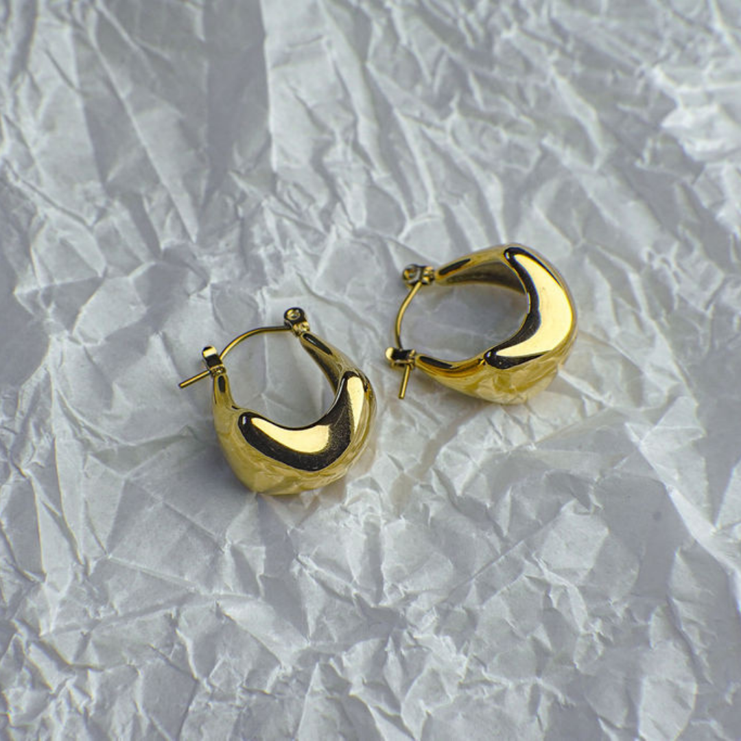 Gold hoop earrings on a textured white surface