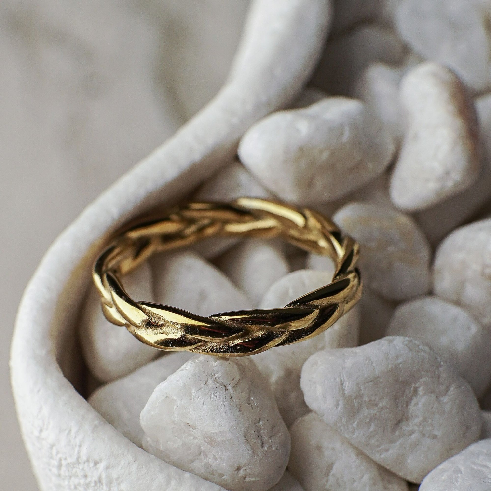 Gold braided ring on white pebbles