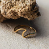 Gold ring on sand with a rock in the background