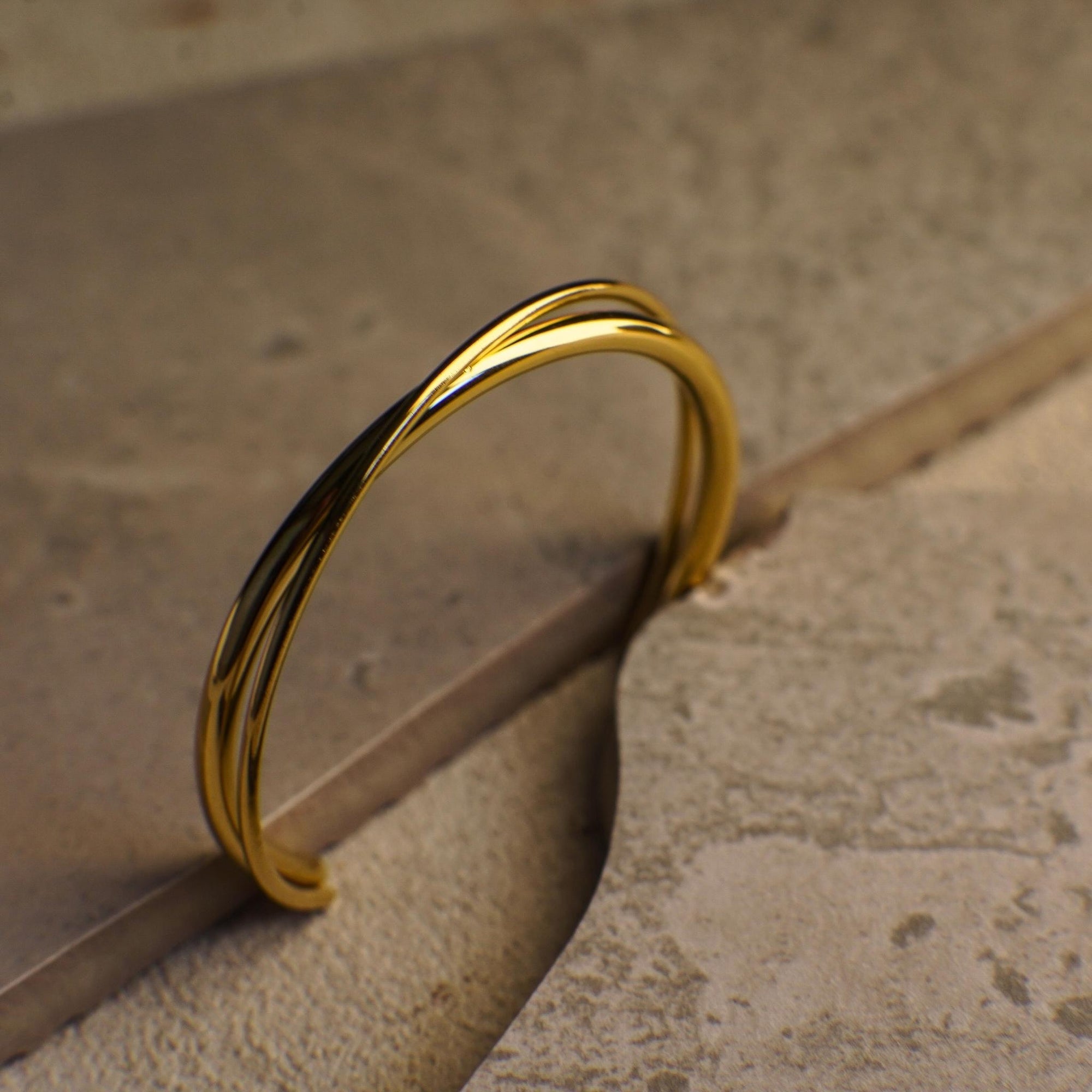Gold twisted bracelet on a textured surface