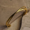Gold twisted bracelet on a textured surface
