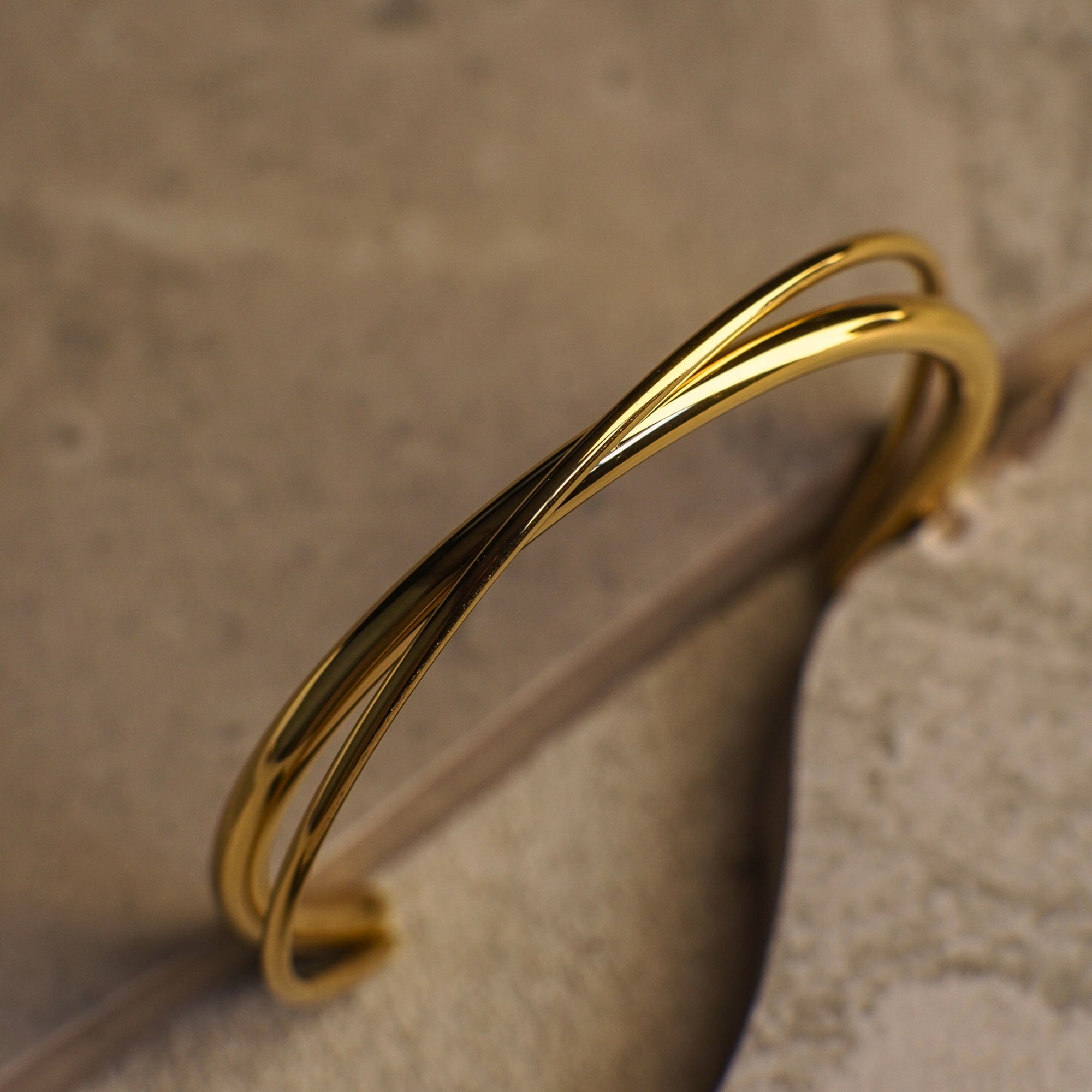 Gold twisted bracelet on a textured surface