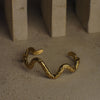 Gold wavy bracelet on a textured surface