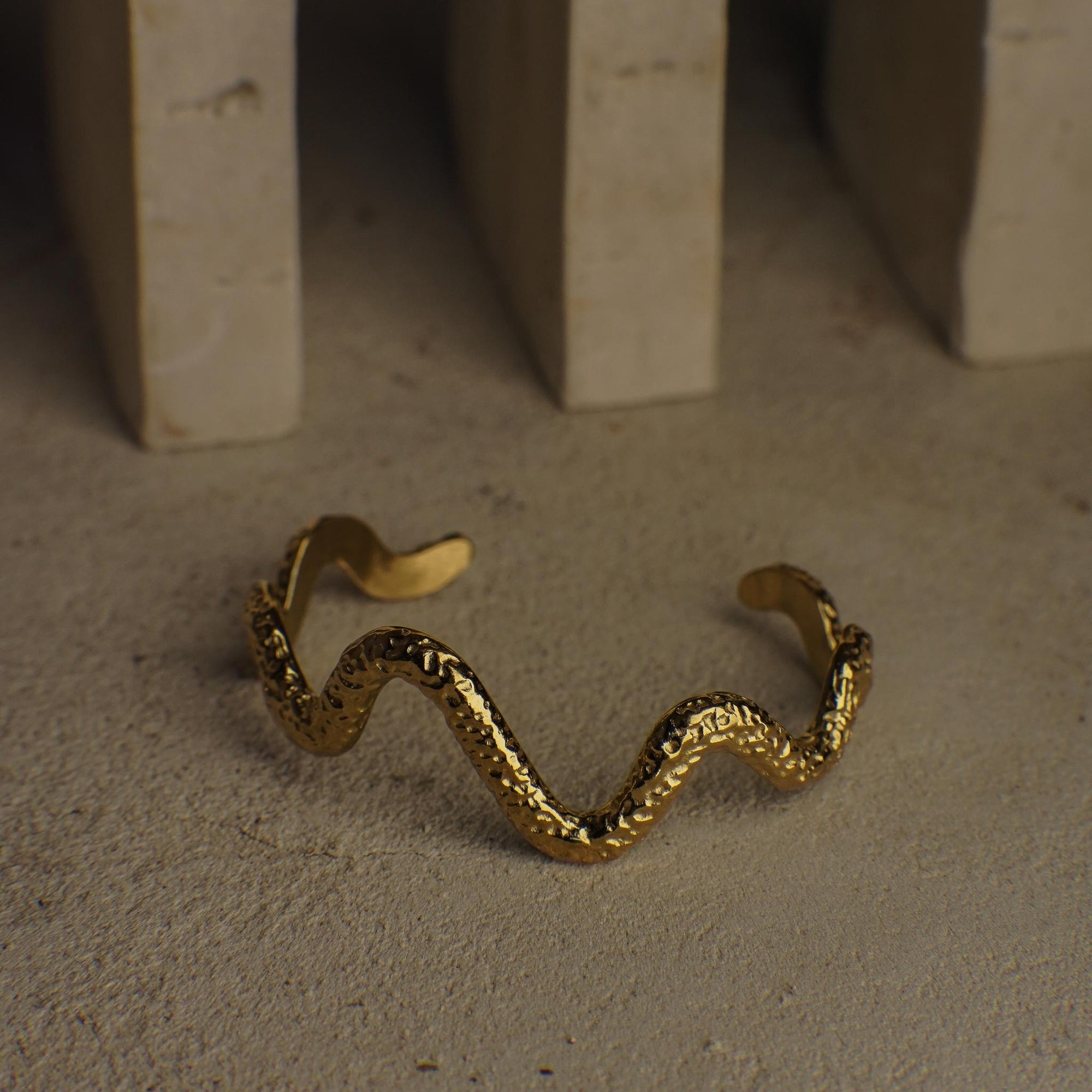 Gold wavy bracelet on a textured surface