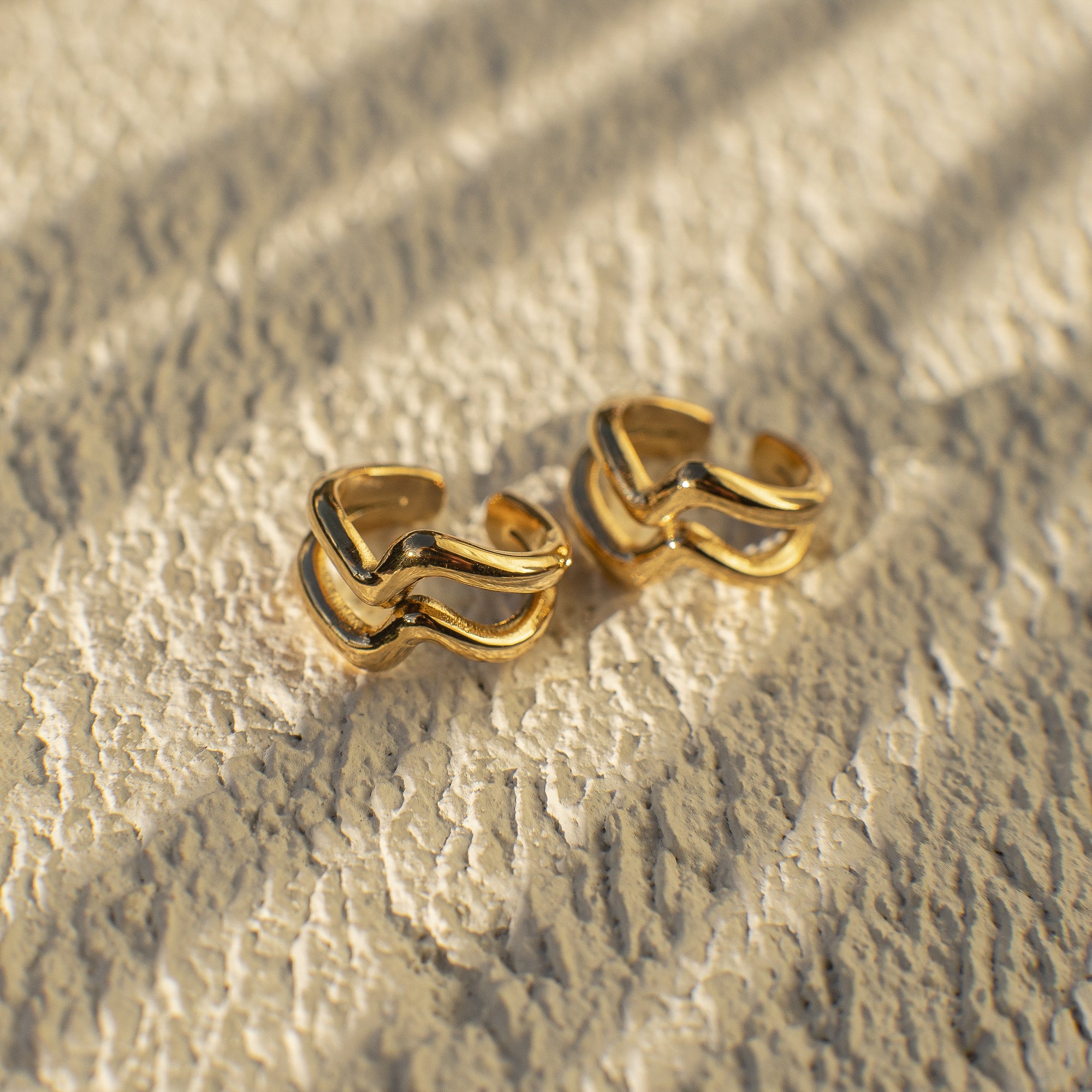 Gold hoop earrings on a textured gold surface