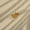 Gold chain earring on a textured beige surface