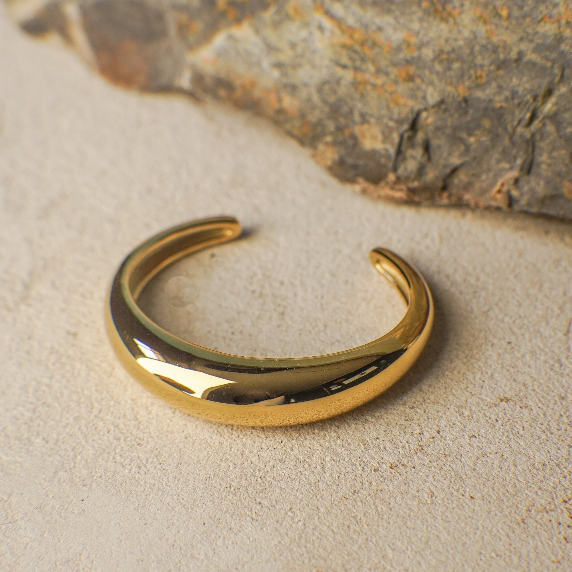 Gold bracelet on a textured stone surface