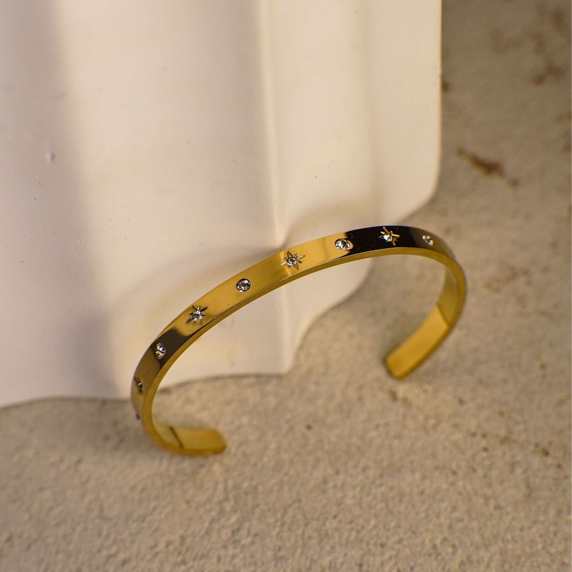 Gold bracelet with star and circle patterns on a textured surface