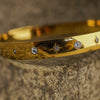 Gold bracelet with gemstone accents on a textured surface