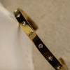 Gold bracelet with star-shaped stones on a neutral background