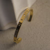 Gold bracelet with star-shaped stones on a neutral background