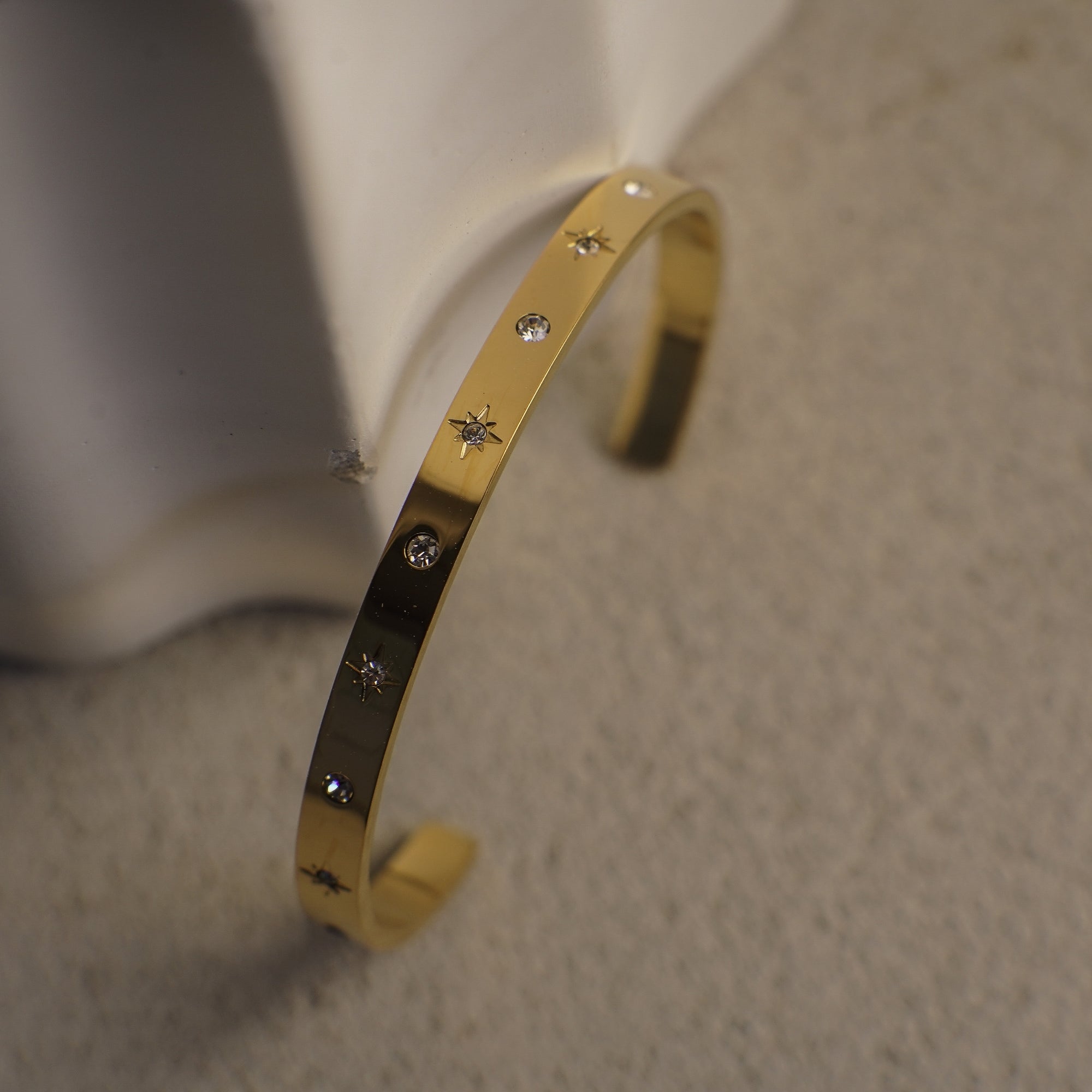Gold bracelet with star-shaped stones on a neutral background