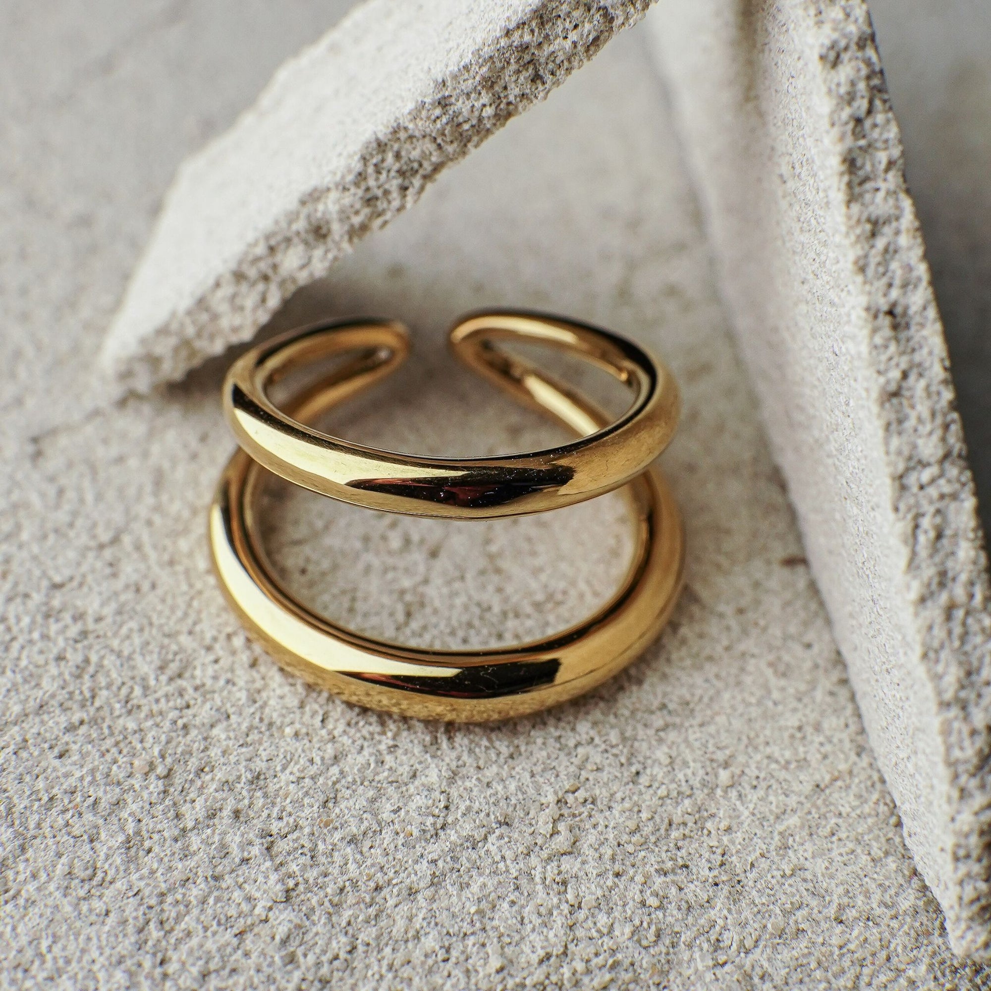 Two gold rings stacked on a textured stone surface