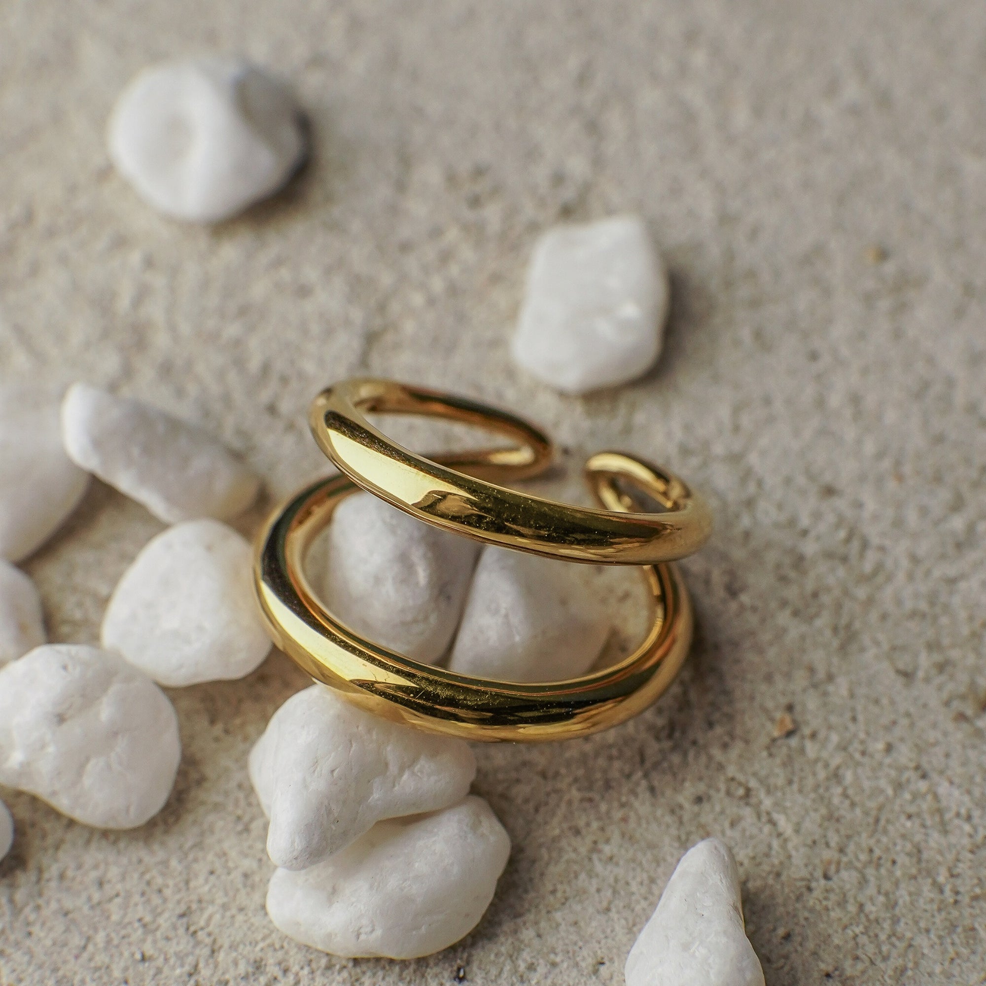 Gold ring on white pebbles with a natural background
