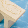 Gold necklace on a beige stand with a blue marble background