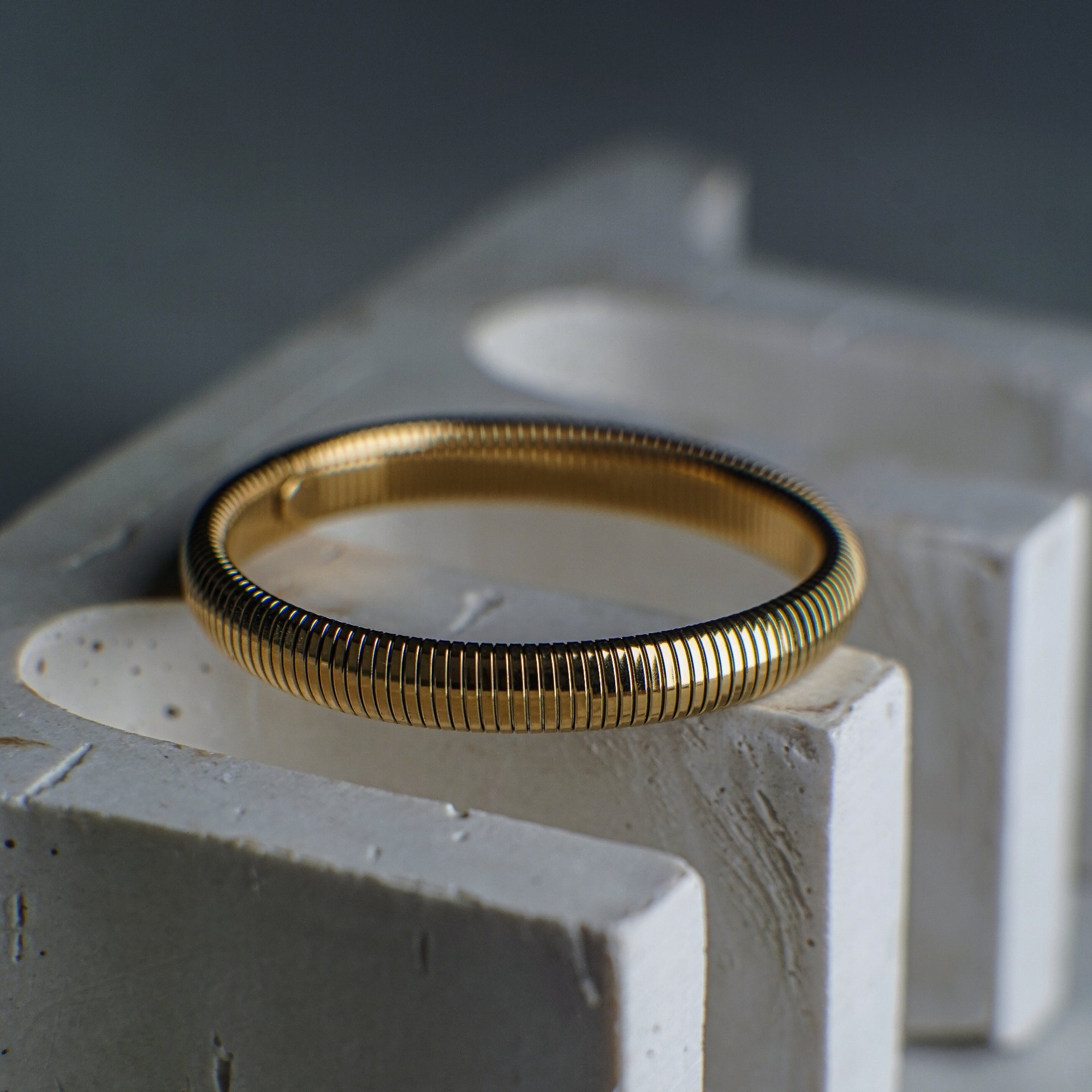 Gold ring on a textured white surface with a blurred background