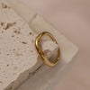 A gold-colored ring placed on a textured stone surface.
