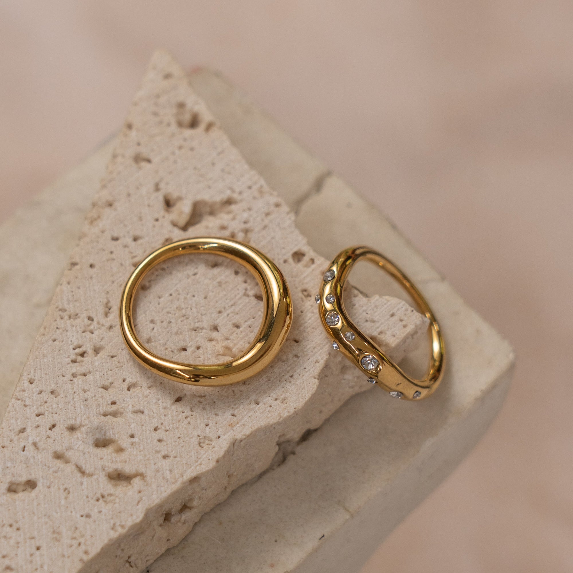 Two gold rings with little crystals on a beige rock