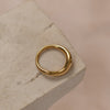 A gold-colored ring placed on a textured stone surface.