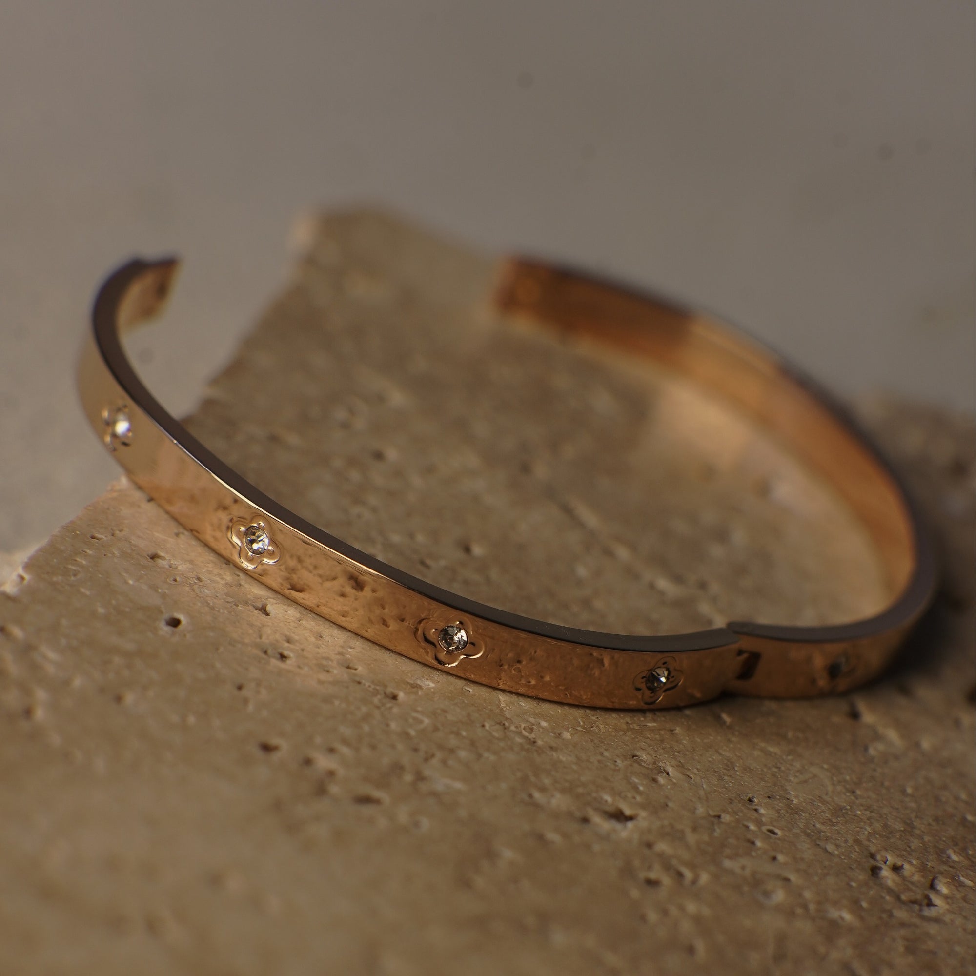 Gold bracelet with small stones on a textured surface