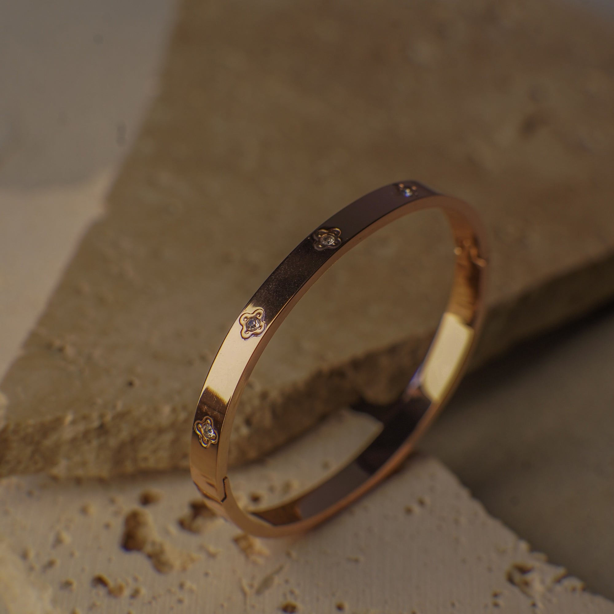 Gold bracelet with diamond accents on a textured stone surface