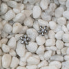 Silver flower-shaped earrings on a bed of small white stones