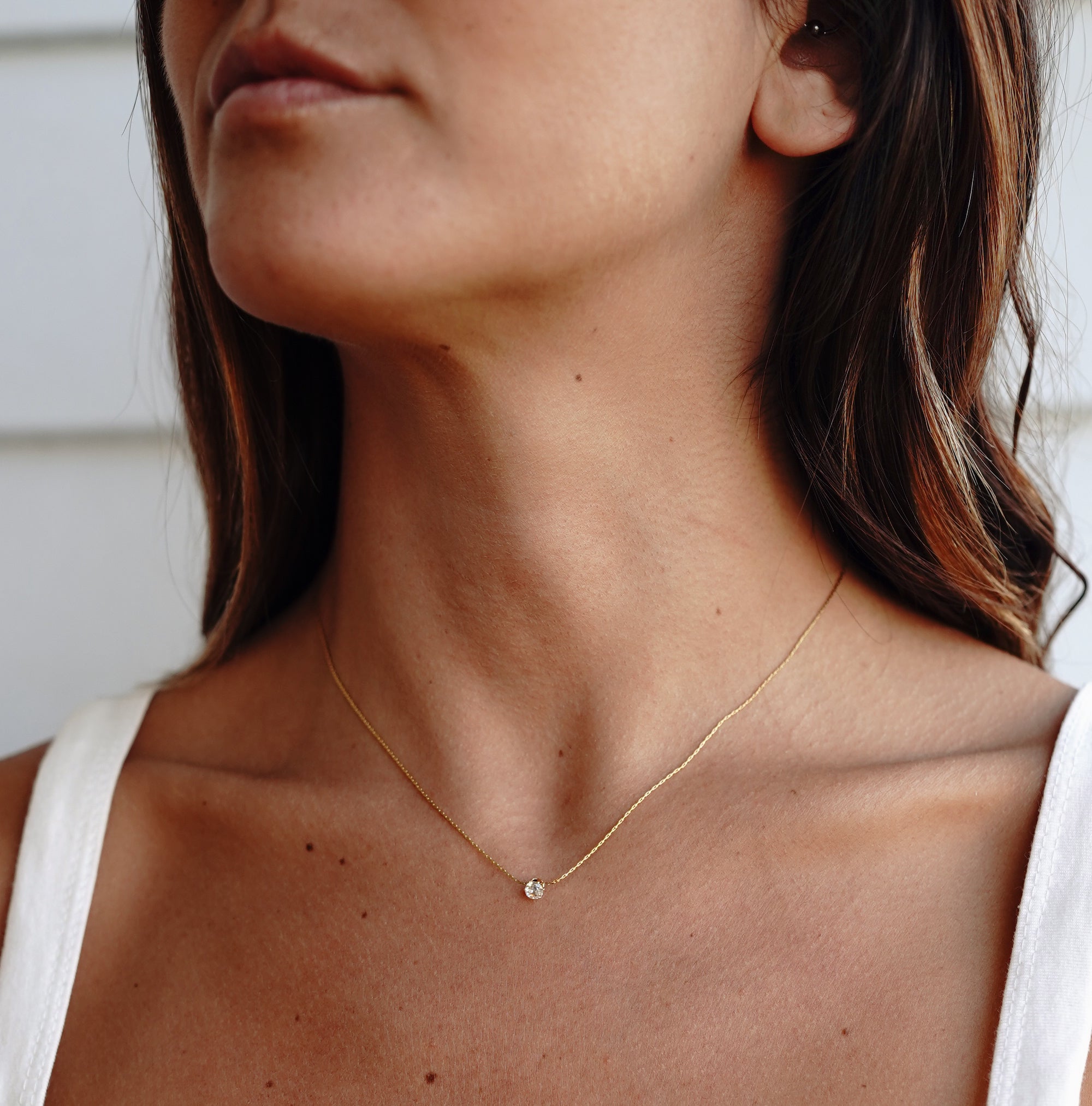 A model wearing gold necklace with cubic zirconia pendant