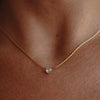 A gold necklace with zirconia pendant on a model's neck