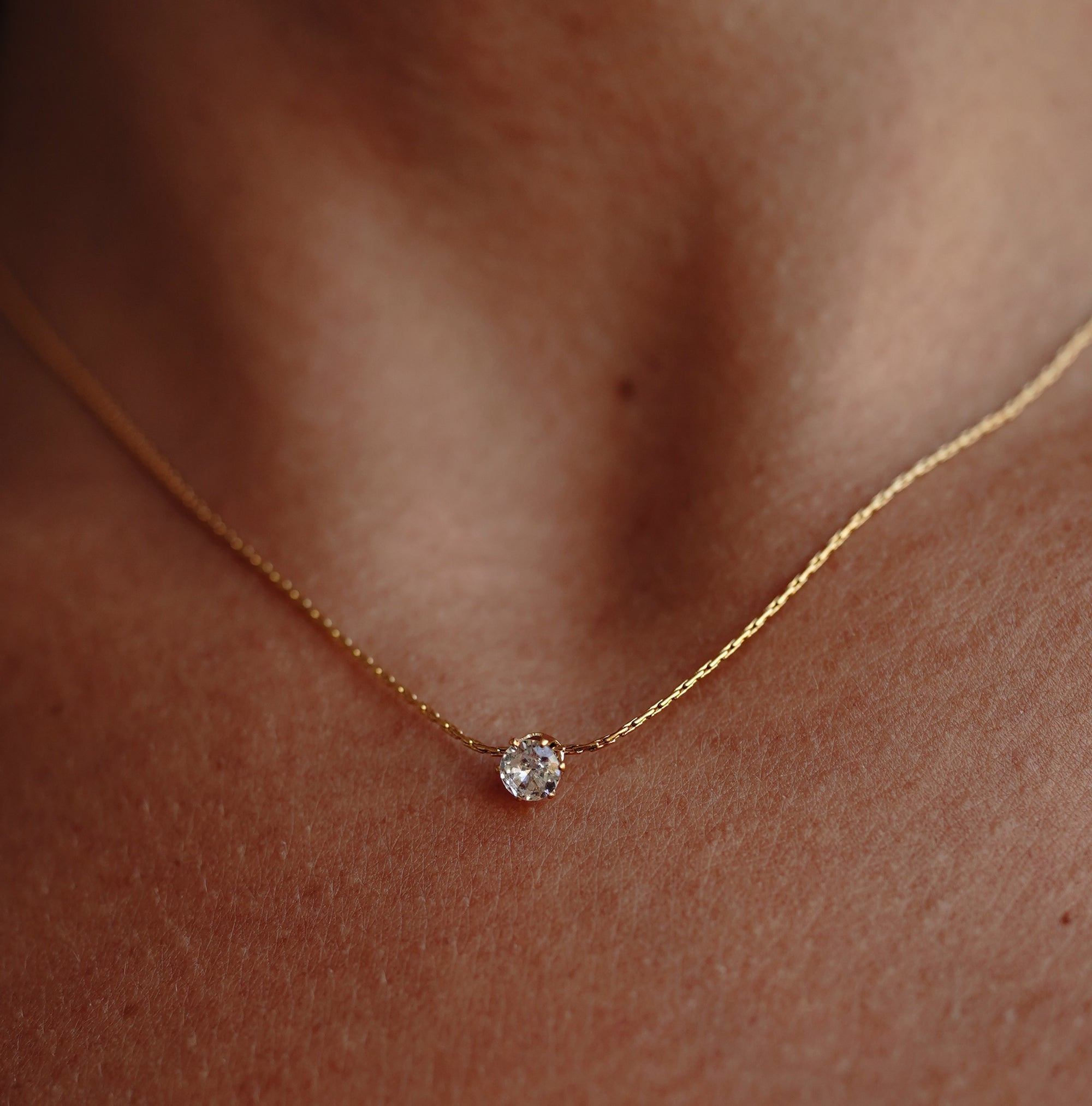 A gold necklace with zirconia pendant on a model's neck