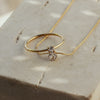 A gold necklace with cubic zirconia pendant paired with a ring that has the same style