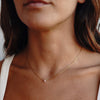 A model wearing a gold necklace with rose quartz pendant