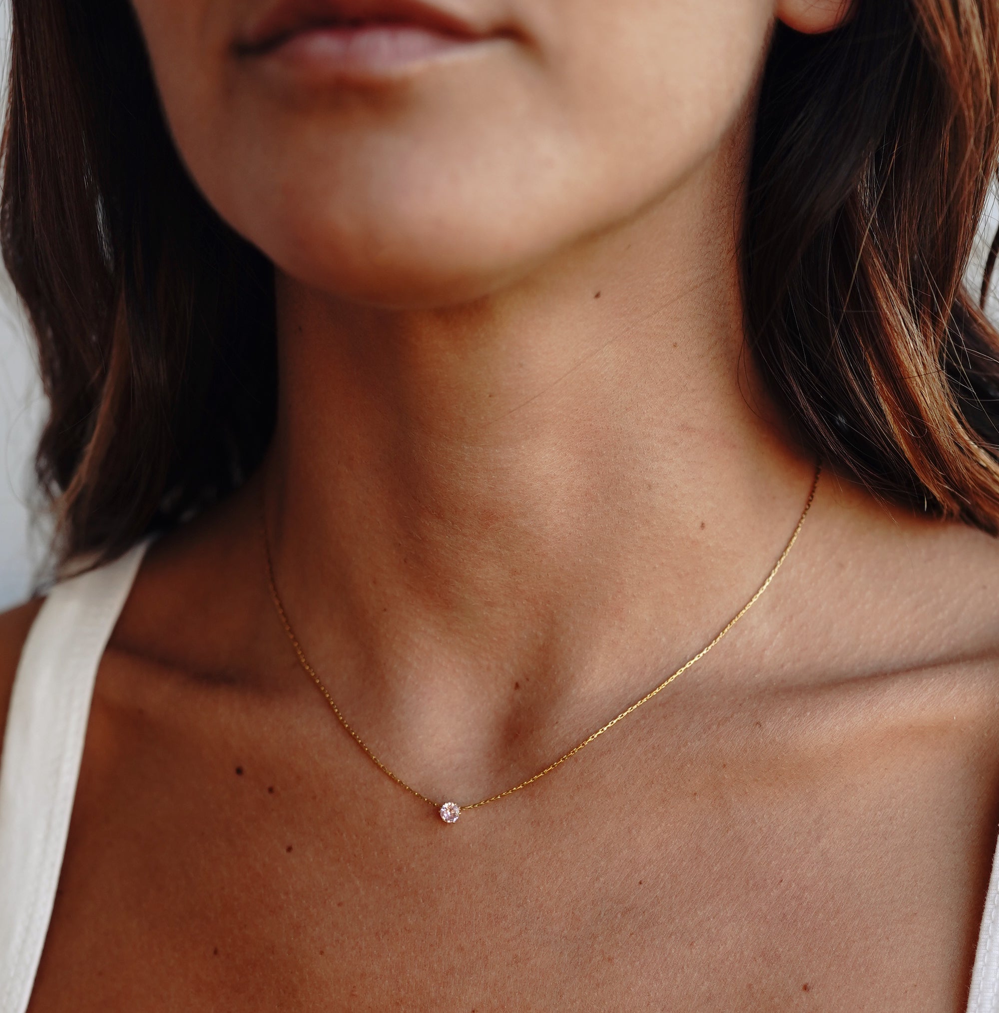 A model wearing a gold necklace with rose quartz pendant