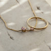 A gold necklace with rose quartz pendant paired with gold ring with rose quartz stone