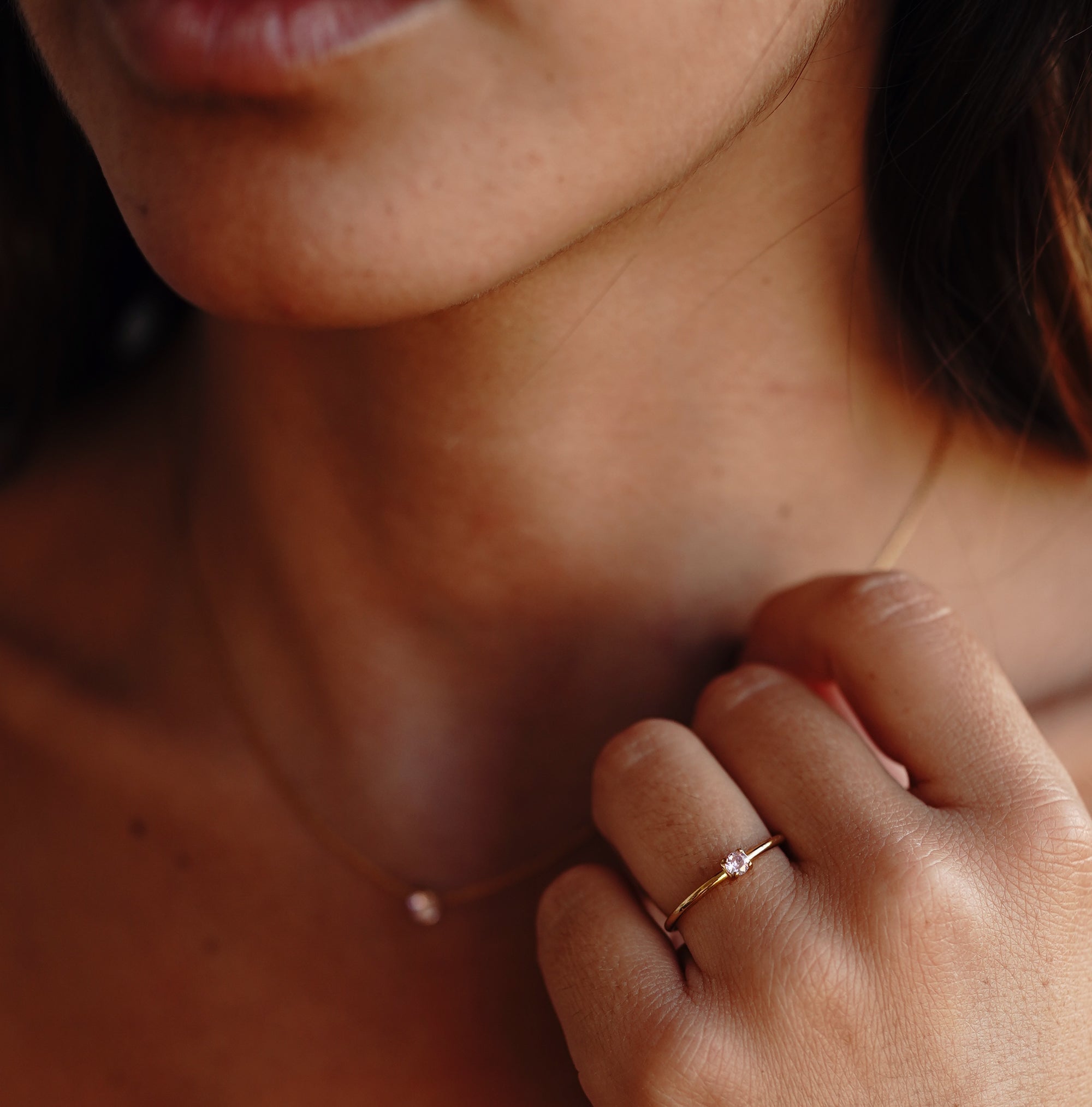 A model wearing a gold necklace with rose quartz pendant paired with the ring with the same features