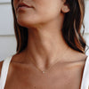 A model wearing gold necklace with cubic zirconia pendant