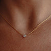 A gold necklace with zirconia pendant on a model's neck