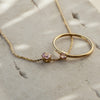 A gold necklace with rose quartz pendant paired with gold ring with rose quartz stone