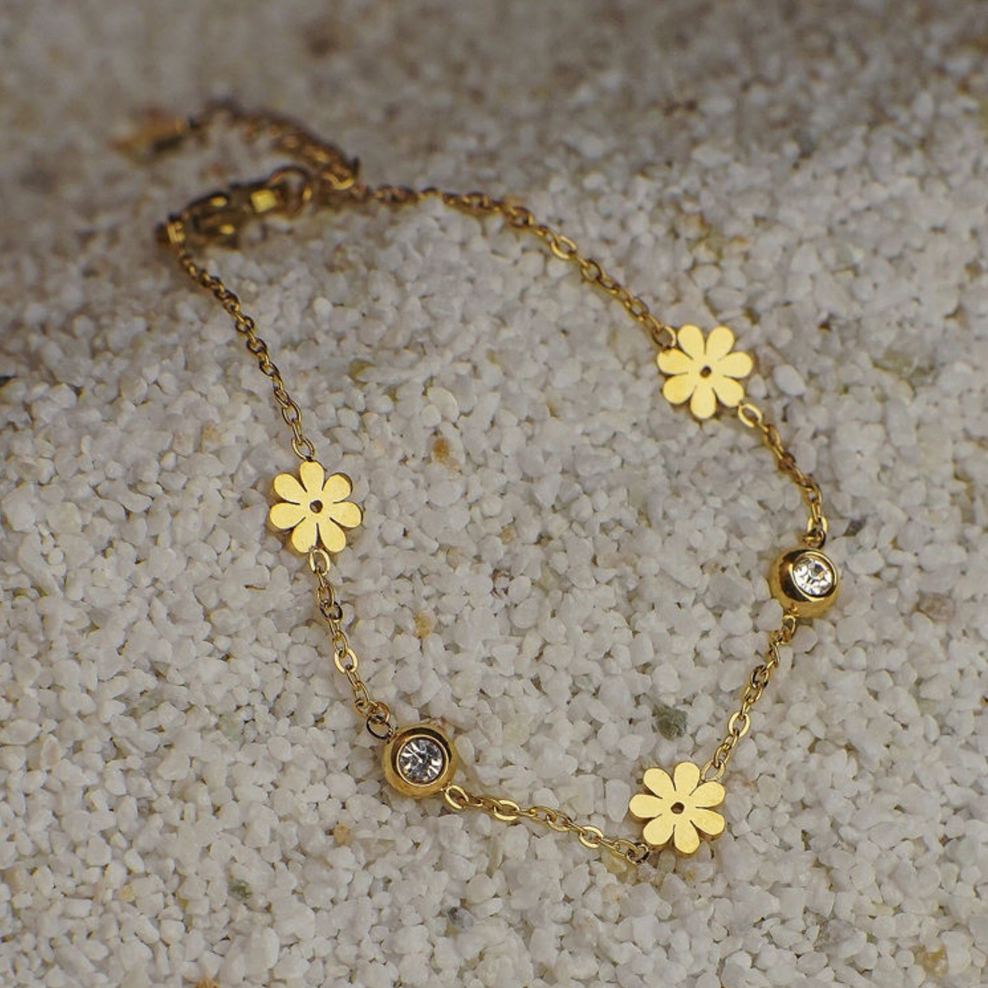Gold bracelet with floral designs on a textured surface
